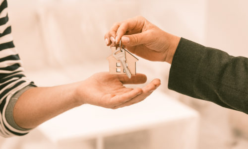 Stock photo of a man's hand passing a woman's hand a key on a keychain